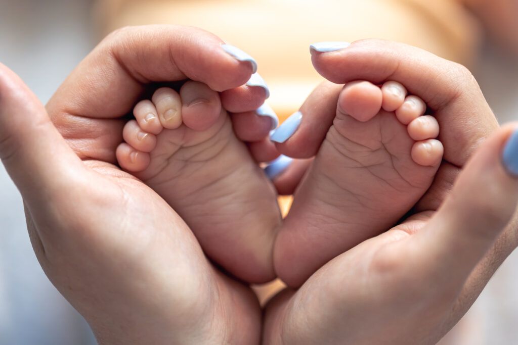 Mom holding feet of newborn baby